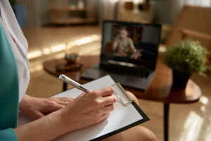 A woman acting as a professional counselor in an emotional support video call with a soldier from her office.