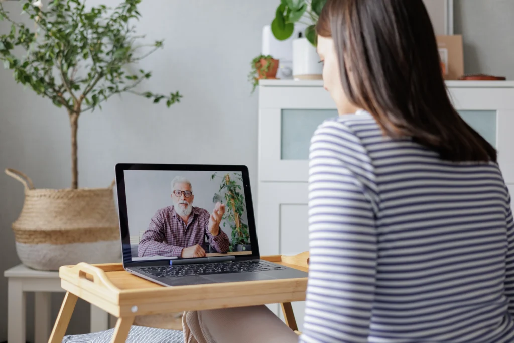 Young woman at home participating in occupational therapy guided by a senior professional via her laptop.