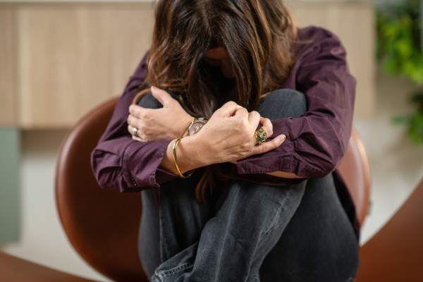 Woman sitting with her arms wrapped around her legs, illustrating the emotional tension associated with various types of anxiety disorders.