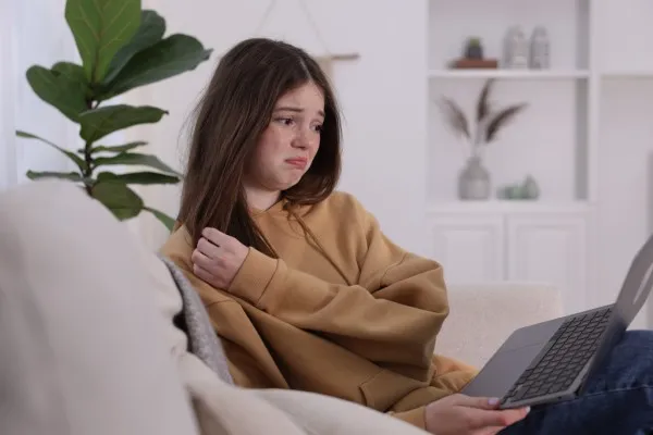 Adolescente con expresi&oacute;n triste frente a su laptop buscando opciones de terapia para depresi&oacute;n y apoyo emocional.