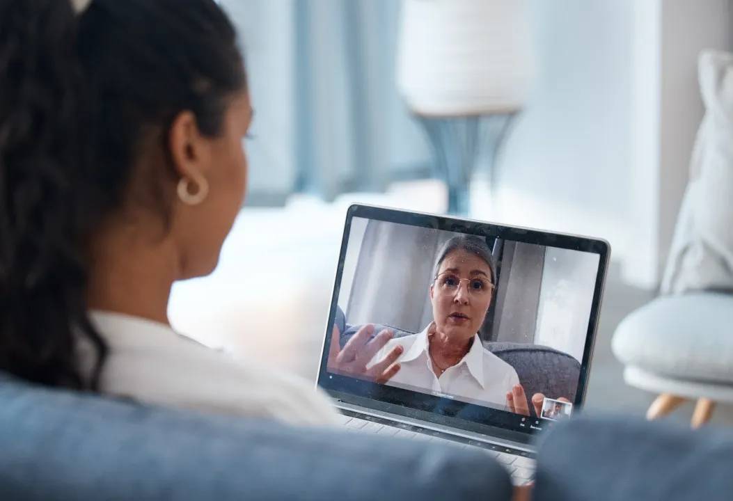 Woman listening attentively to her psychologist on screen during an online Acceptance and Commitment Therapy session.